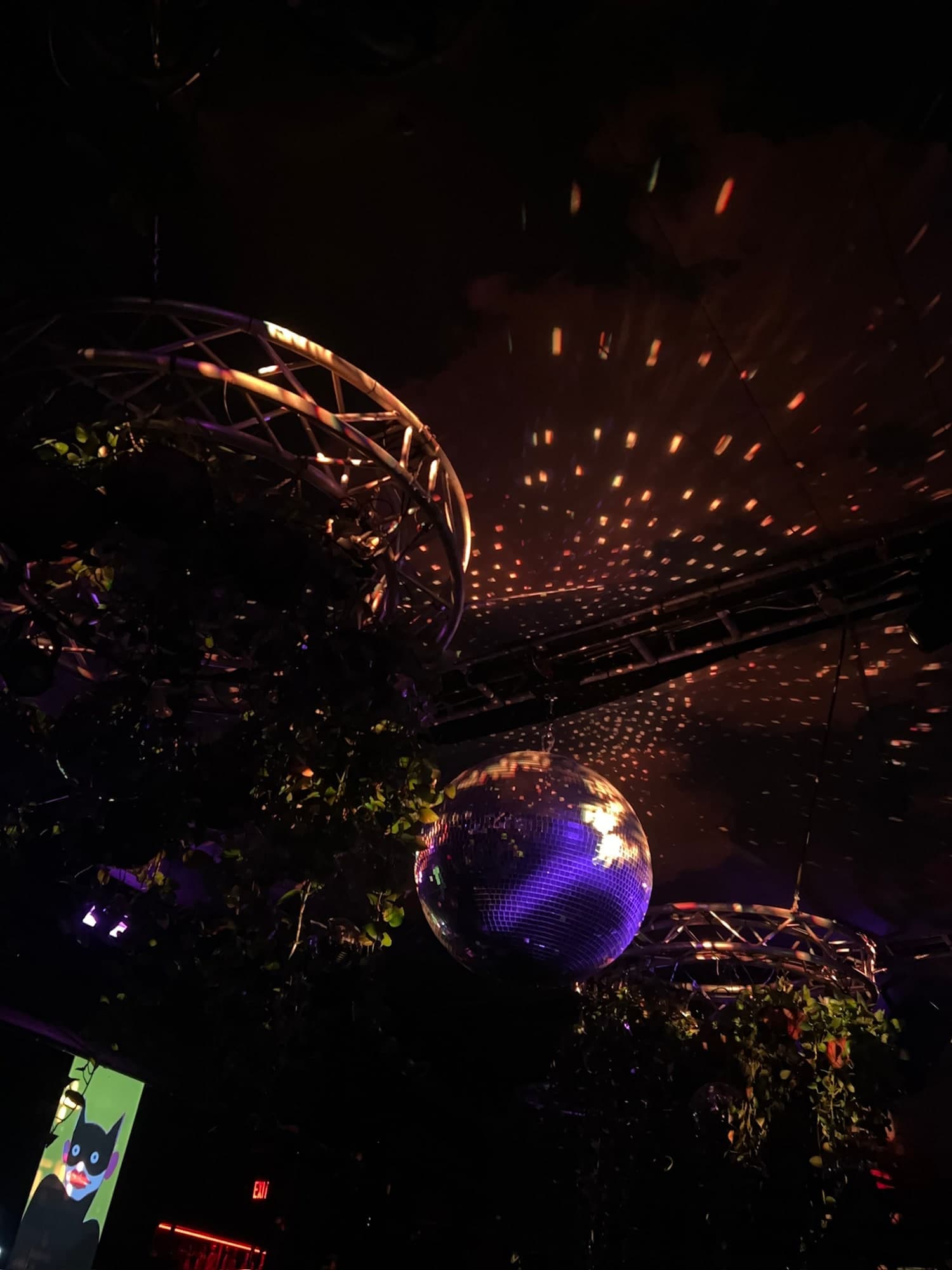 A disco ball above a Miami nightclub, with colored light scattered across the ceiling.