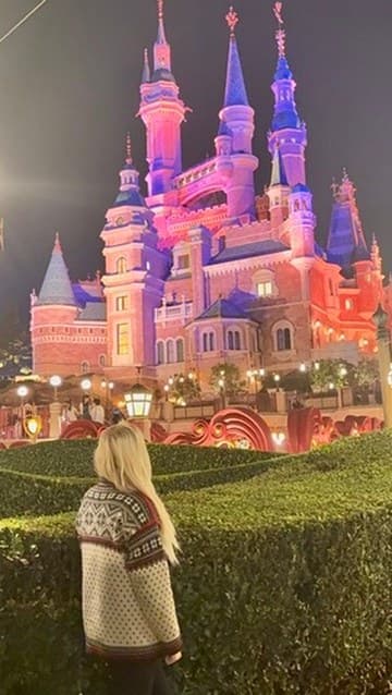 Hannah looking toward Shanghai’s castle illuminated in pink and purple at night.