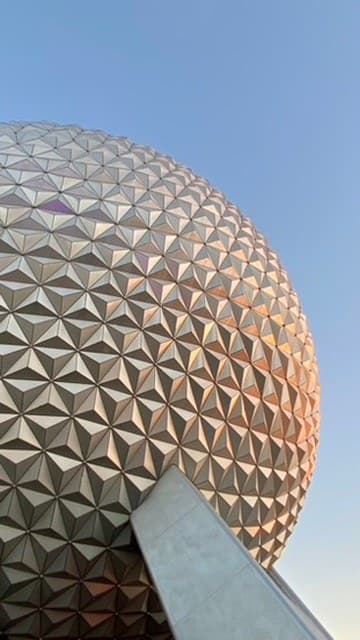 EPCOT’s Spaceship Earth geodesic sphere in warm light against a blue sky.