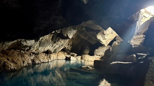 A shaft of daylight entering Grjótagjá cave above its blue geothermal pool.