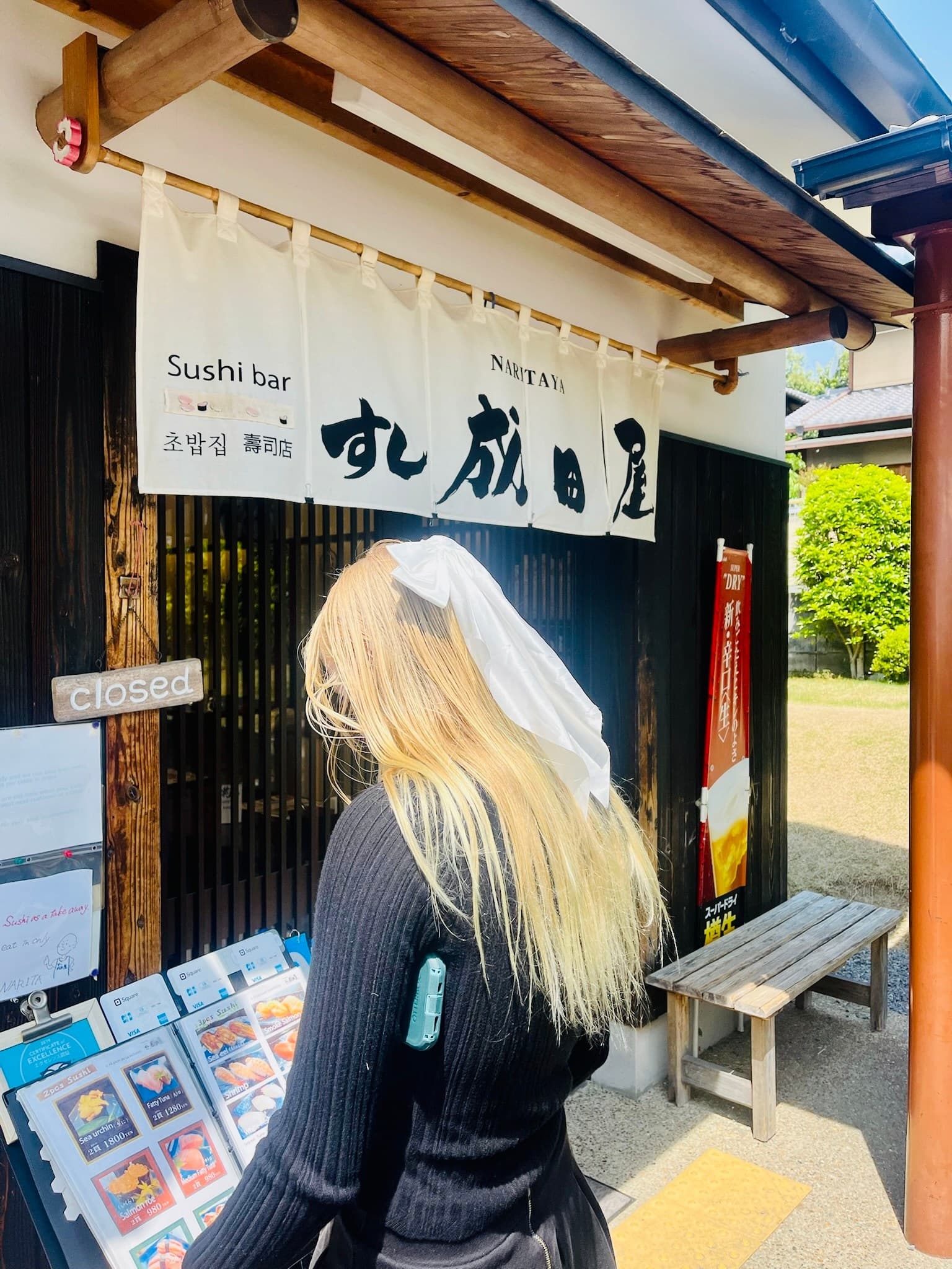 Hannah with a white ribbon in her hair outside Sushi Naritaya in Arashiyama, Kyoto, Japan