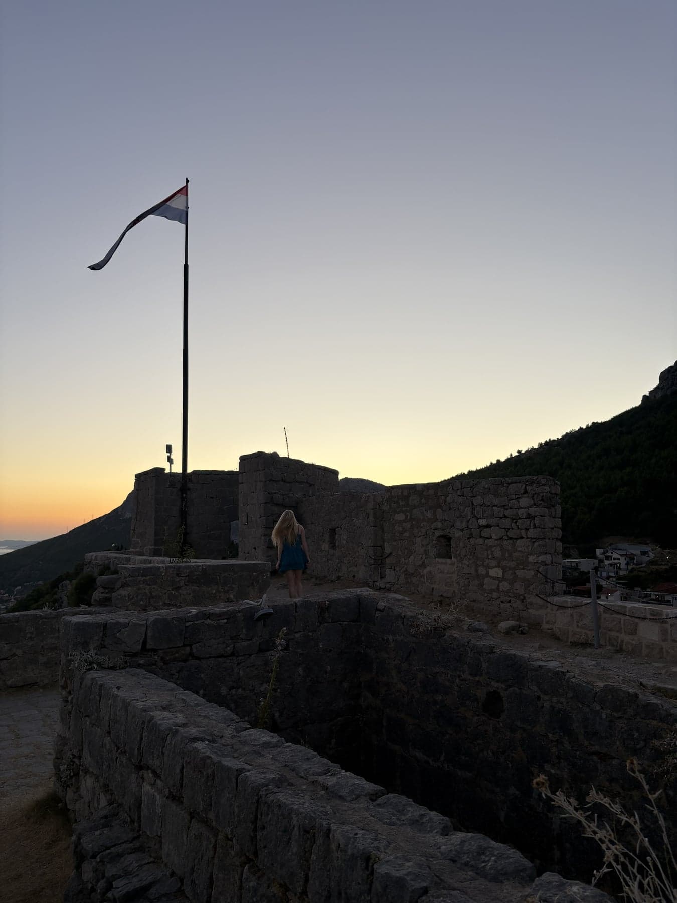 Stone walls of Klis Fortress with the Croatian flag above them