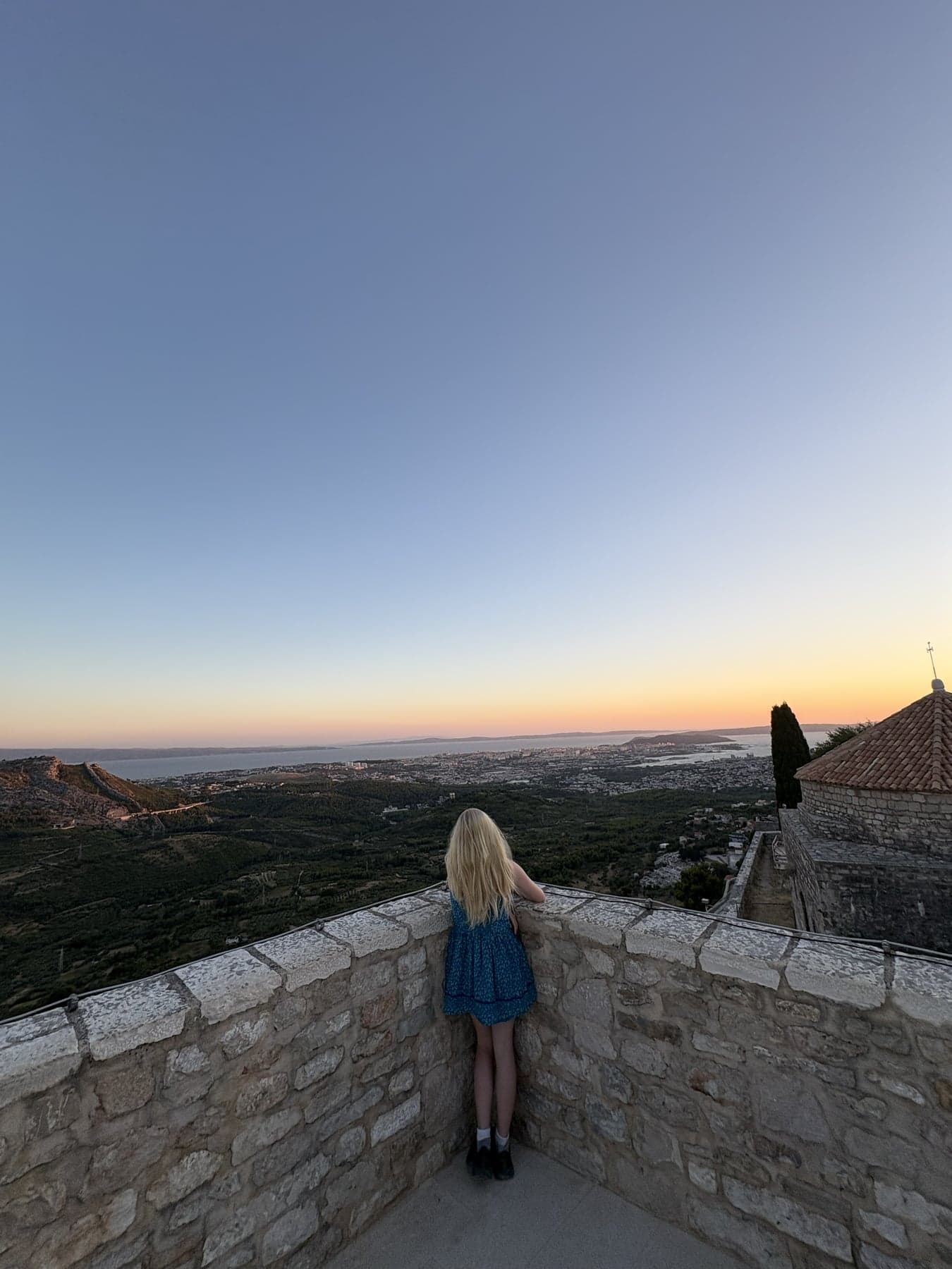 Hannah standing beside the stone walls at Klis Fortress, looking toward Split and the coast