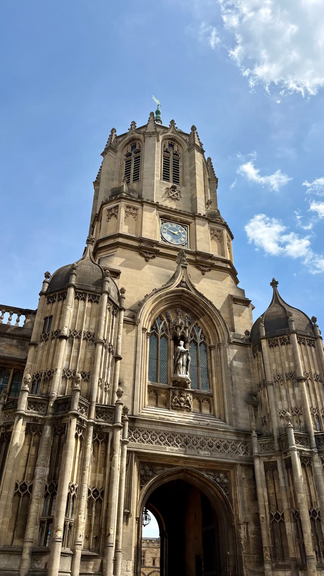 An ornate stone clock tower above an arched gateway in Oxford.